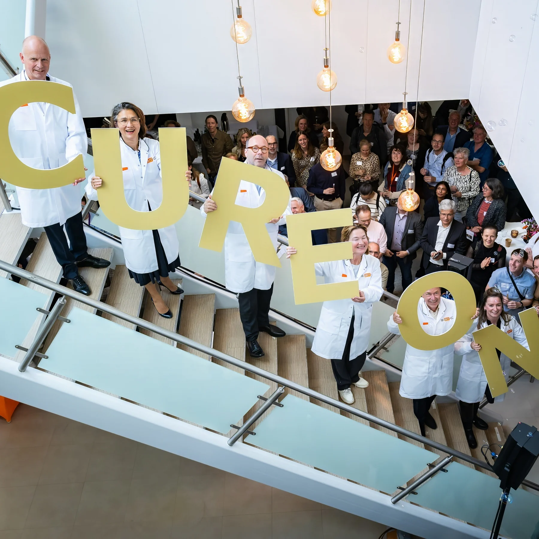 People on stairs holding letters that spell CUREON