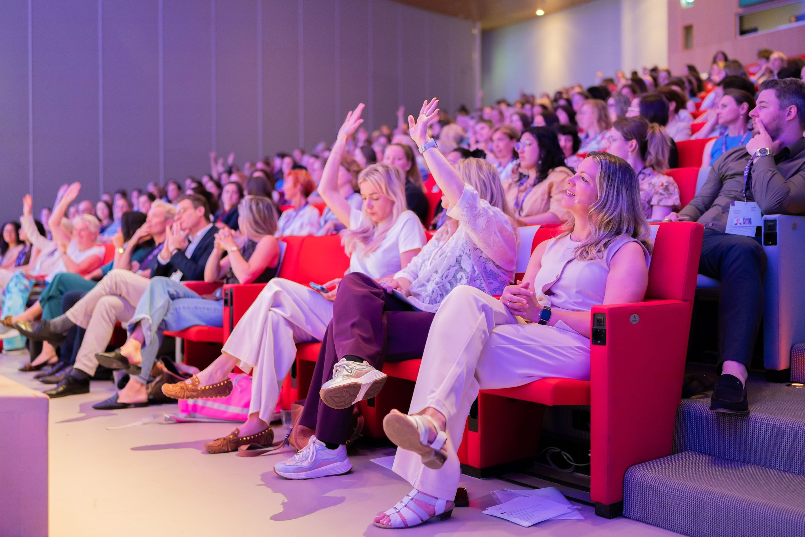 People in auditorium raising their hands