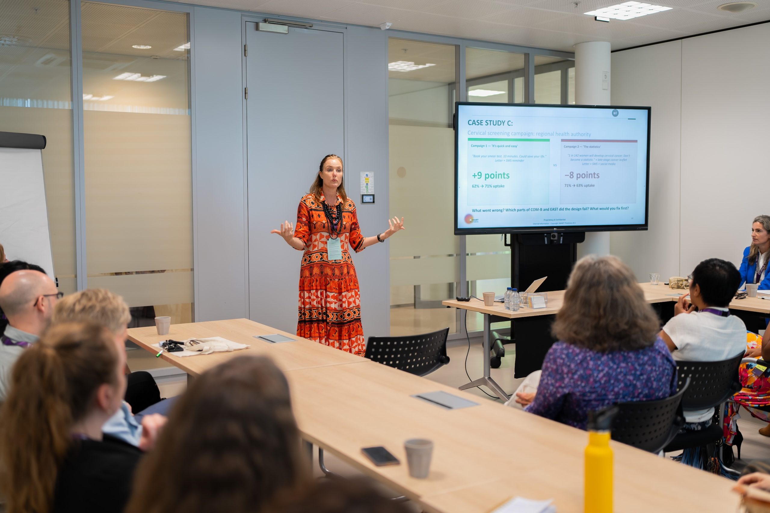 A woman gestures in front of a screen in a workshop